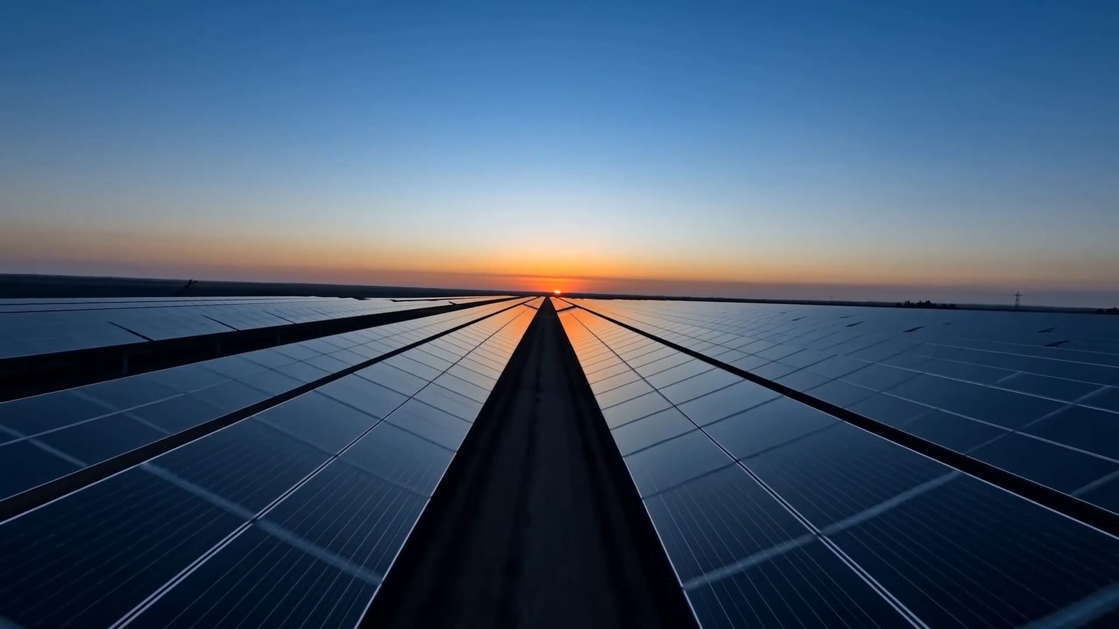 File di moduli di un impianto fotovoltaico a terra al tramonto